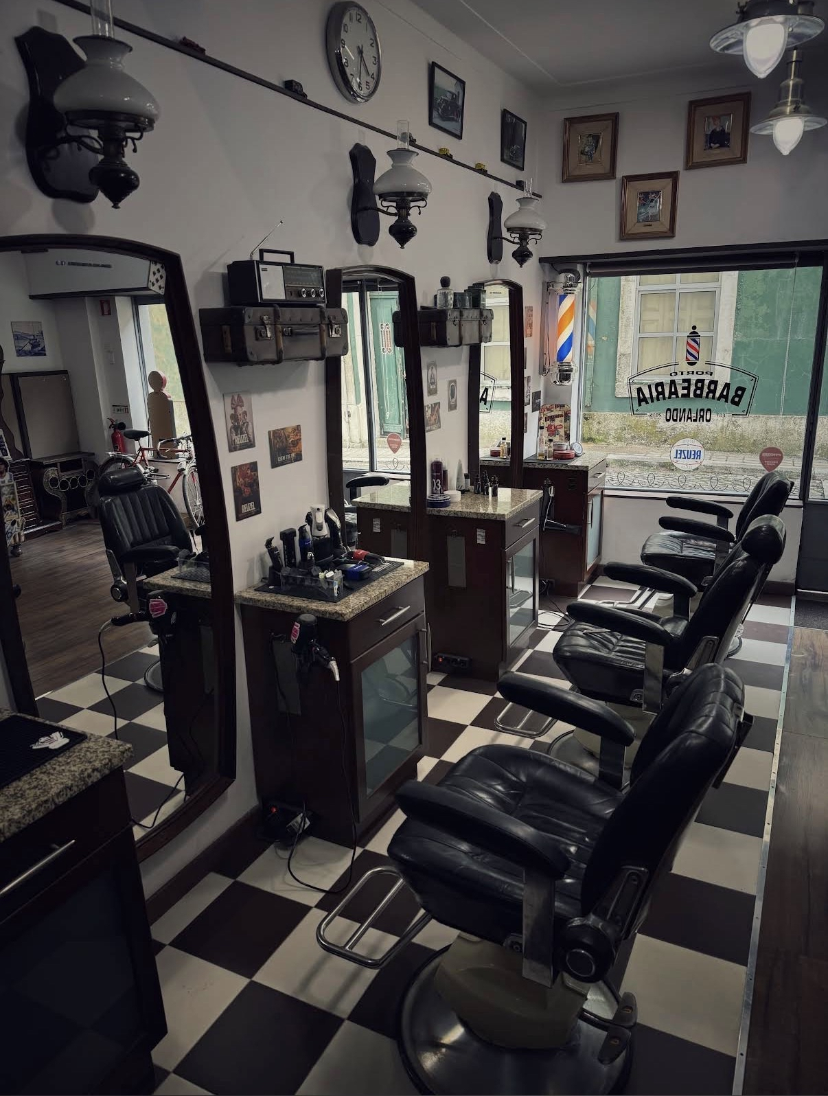 Interior da Barbearia Orlando: cadeiras clássicas em pele, chão axadrezado e decoração vintage